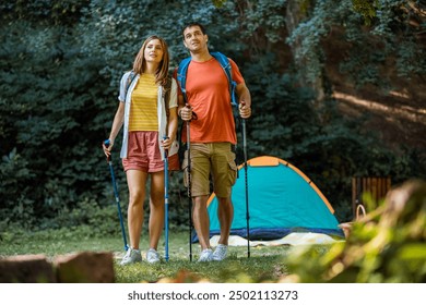 Married couple preparing to start their hiking routes. Tent is behind them and they have hiking poles and other equipment for hiking. - Powered by Shutterstock