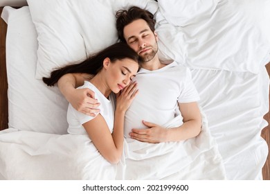 Married Couple Sleeping Together Embracing Lying In Comfortable Bed At Home At Night. Top View Shot Of Spouses Resting Peacefull Enjoying Nap In Comfortable Bedroom