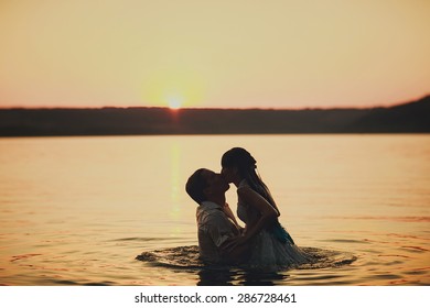 Married Couple Is Swimming In The Lake At Sunset