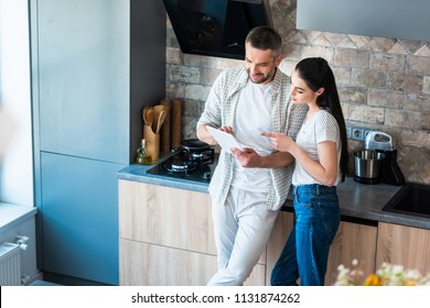 married couple using digital tablet together in kitchen, smart home concept - Powered by Shutterstock