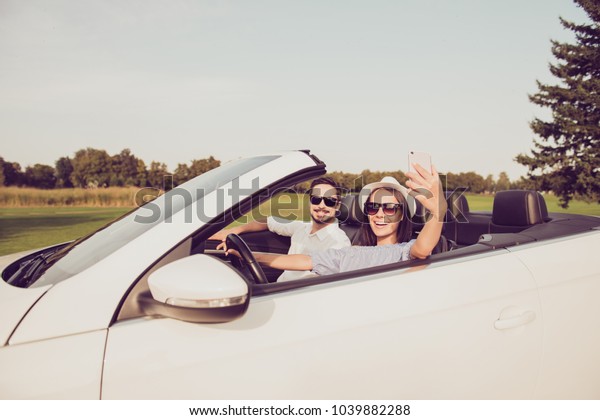 Married family, relax escape, tourism destination,\
speed ride drive lifestyle. Carefree driver lady wife with camera\
take shot, make memories of honeymoon road trip, husband brunet sit\
near in specs