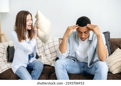 A Married Multiracial Couple Sorts Things Out While Sitting In The Living Room On A Sofa, A Caucasian Woman Screams At Her Hispanic Husband. Misunderstanding In Relationships, Jealousy, Quarrel