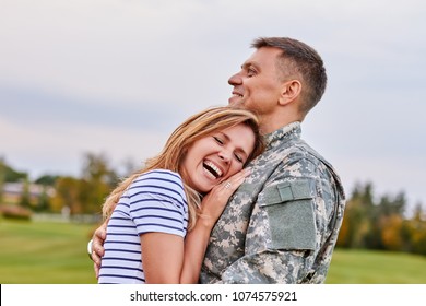 Married soldier hugging wife outdoor. Woman is very happy her husband is back from the army. - Powered by Shutterstock