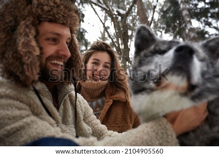 Married young couple on a walk in the winter forest with a pet dog husky