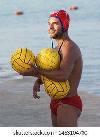 Marsaxlokk, Malta - 8 Jul, 2019: Portrait Of Sportman Athlete From Water Polo Team With Red Water Polo Cap Posing With Three 3 Yellow Balls,after Training In The Pool.Sportman. Water Sport