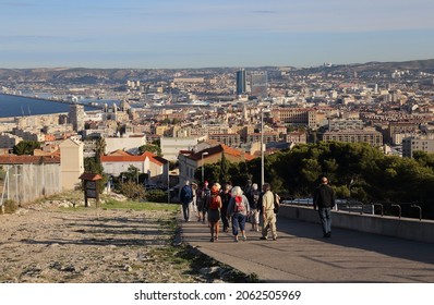 Marseille, France - September 28, 2019: Group of tourists and cityscape of Marseille with the harbor and ships, seen from the site of the Notre Dame church in Marseille, France on September 28