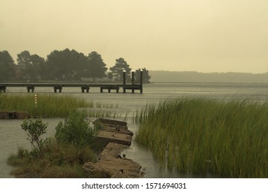 Marsh In The Chesapeake Bay Area With A Dock In The Background On A Rainy Day