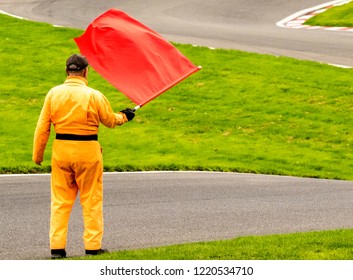 A Marshal At A Racetrack Holds Up A Red Flag To The Rider(s).