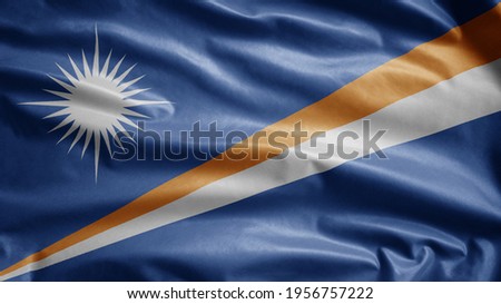 Marshallese flag waving in the wind. Close up of Marshall banner blowing, soft and smooth silk. Cloth fabric texture ensign background. Use it for national day and country occasions concept.
