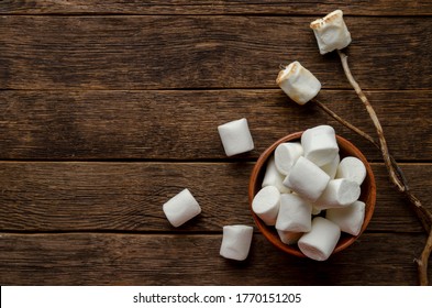 Marshmallow on the stick on wooden background