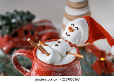 Marshmallow snowman taking hot tub in a red ceramic cup full of cocoa with milk foam. Christmas holidays layout. Wintertime concept. Hot chocolate with marshmallow and festive decoration. - Shutterstock ID 2239058363