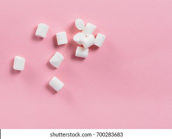 Marshmallows on pink background with copyspace. Flat lay or top view. Background or texture of colorful mini marshmallows. Winter food background concept.