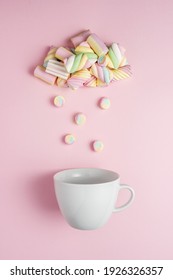 Marshmallows in shape of rainy cloud with white cup on pink background. Creative minimal sweet holiday food concept.