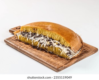 Martabak manis or terang bulan is indonesian sweet pancake, with yellow color and filled with chocolate chips, cheese, fruit jam, butter and peanut on white background.