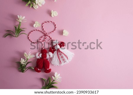 Martenitsa, Martisor among spring flowers on a pink background flat lay copy space