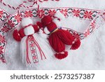 Martenitsa, Martisor, in snow with ribbon with folk ornament with copy space