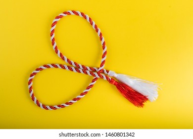 Martenitsa. Symbols of spring, romanian "martisor", "1 martie" symbol. Baba Marta holiday. Tradition in Bulgaria. Baba Marta Day. Wallpaper of martenitsa twisted red and white string.