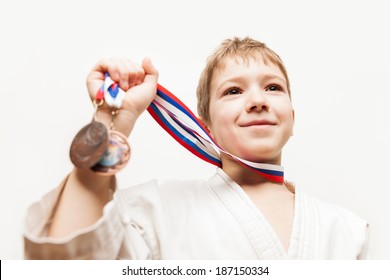 Martial Art Sport Success And Win Concept - Smiling Karate Champion Child Boy Hand Holding First Place Victory Gold Medal Award