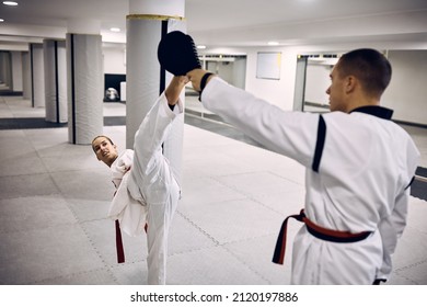 Martial artist with para-ability exercising high kick with her sparing partner while practicing taekwondo in health club.  - Powered by Shutterstock