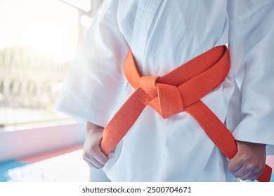 Martial arts, belt and student in studio for fitness, training and fight with orange bow and discipline. Girl, kung fu and ready in dojo as workout for self defense, karate and taekwondo development