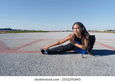 Martial arts girl doing stretching exercises on an airport runway on a sunny day with blue sky. - Powered by Shutterstock