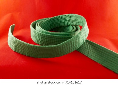 Martial Arts Green Belt Isolated With A Red Background