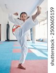 Martial arts, kick and girl in studio for fitness, training and fight with orange belt, development and energy. Student, kung fu and portrait in dojo as workout for self defense, karate and taekwondo