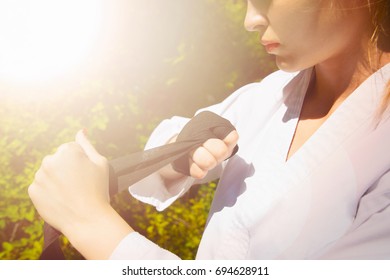 A martial arts master is wrapping a sports bandage around her arm. Image with the effect of sunlight - Powered by Shutterstock