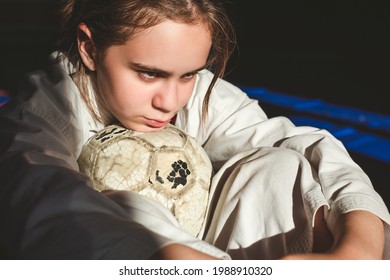 Martial arts training. Beautiful teen girl in a white kimono with a shabby soccer ball is resting after the game.  - Powered by Shutterstock