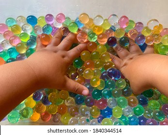 Martinez, CA / USA - October 25, 2020: Toddler's hands playing in colorful water beads, water orbs, gel beads