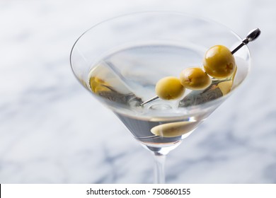 Martini cocktail with green olives on marble board. Close up.
