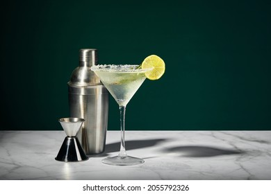 Martini glass with cocktail or mocktail and lime wedge, shaker and jigger on dark background. - Powered by Shutterstock