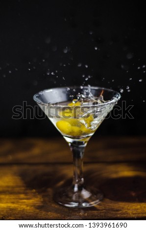 Martini glass with olive splash on dark background