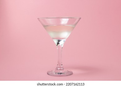 Martini glass on a pink background. Delicious alcoholic drink.