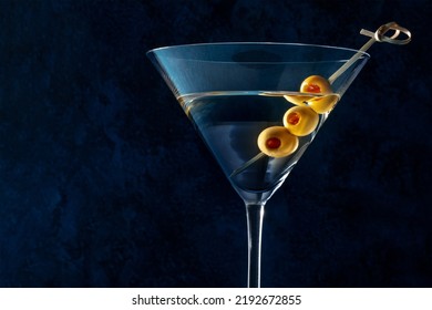 Martini, a glass with spicy olives on a toothpick, on a dark background. Alcoholic cocktail with copy space - Powered by Shutterstock