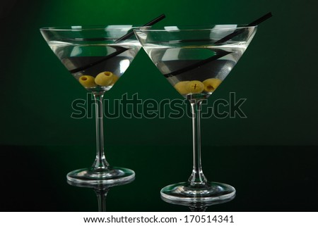 Martini glasses with olives on dark green background