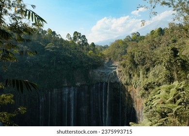 Marvel at the majestic Tumpak Sewu Waterfall glistening under the sunlight. The cascading waters create a breathtaking display - Powered by Shutterstock