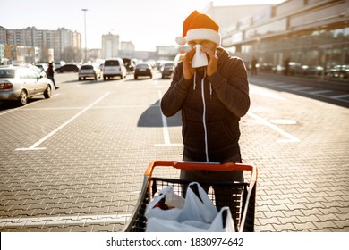 Mary Christmass Happy New Year. Man In Red Santa Claus With Handkerchief. Sick Guy Has Runny Nose. Male Model Makes A Cure For The Common Cold Makes Purchases At The Supermarket Or Shopping Mall