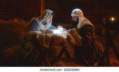 Mary and Joseph caressing baby Jesus in illuminated manger - Shutterstock ID 2026520804