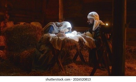 Mary and Joseph caressing baby Jesus in illuminated manger - Shutterstock ID 2026520813
