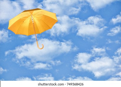 Mary Poppins Umbrella.Yellow umbrella flies in sky against of white clouds.Wind of change concept.