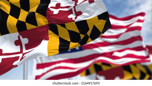 The Maryland state flag waving along with the national flag of the United States of America. In the background there is a clear sky. Maryland is a state in the Mid-Atlantic region of the United States