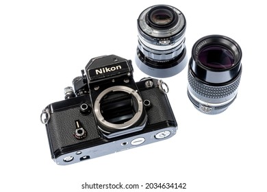 Maryville, Tennessee, United States – August 27, 2021: Horizontal angled front shot of a black Nikon F2S single-lens reflex camera body laying on it’s back with a 35mm and 105mm lenses next to it isol