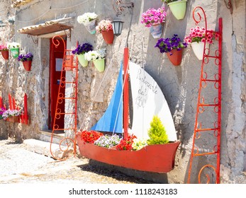 Marzamemi, Sicily - May 20 2018 : Old Colored Ship And Nice Red Decorations In Front Of A Shop