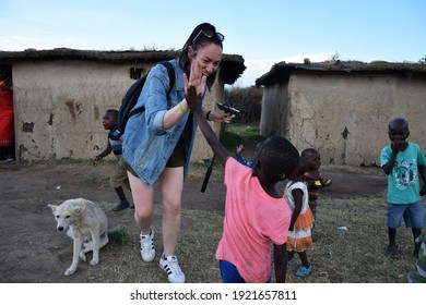 Masai Mara, NA, Kenya - August 15 2018: Tourist ￼clashes His Hand With Several Unknown Children From A Masai Tribe In Kenya