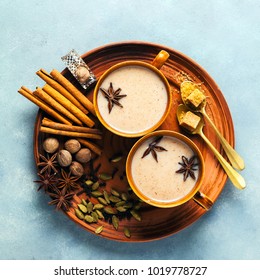 Masala tea chai latte traditional hot Indian teatime ceremony sweet milk with spices, herbs organic infusion healthy beverage in porcelain cup on blue table background