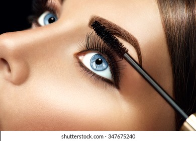 Mascara applying closeup, long lashes. Mascara brush. Eyelashes extensions. Make-up for blue eyes. Eye make up apply