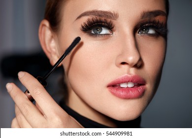 Mascara. Closeup Of Beautiful Young Woman Face With Beauty Makeup, Fresh Soft Skin And Long Black Thick Eyelashes Applying Mascara With Cosmetic Brush. Make-up And Cosmetics Concept. High Resolution