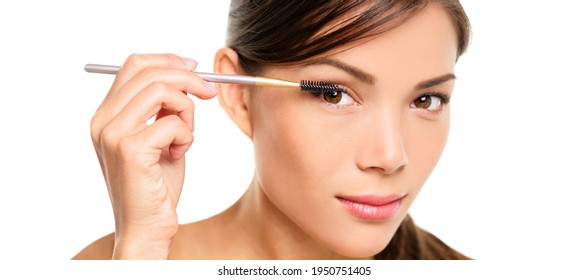 Mascara Woman Putting Makeup On Eyes. Asian Female Model Face Closeup With Eye Brush On Eyelashes. Portrait Isolated On White Background.