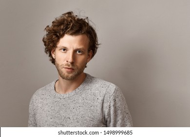 Masculine Beauty, Style And Fashion Concept. Fashionable 25 Year Old Hipster Guy With Stubble And Blue Eyes Posing Isolated Against Copyspace Wall Background, Wearing Stylish Knitted Sweater